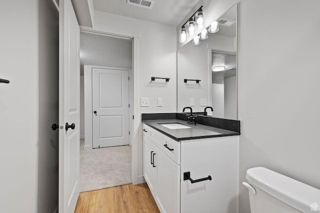 bathroom with visible vents, vanity, toilet, and wood finished floors