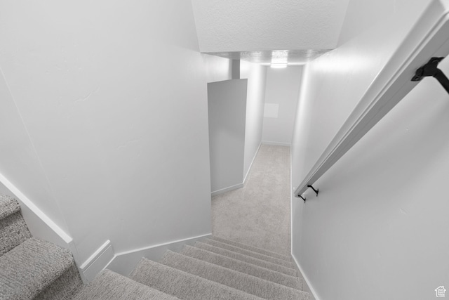 stairway with carpet floors, a textured ceiling, and baseboards