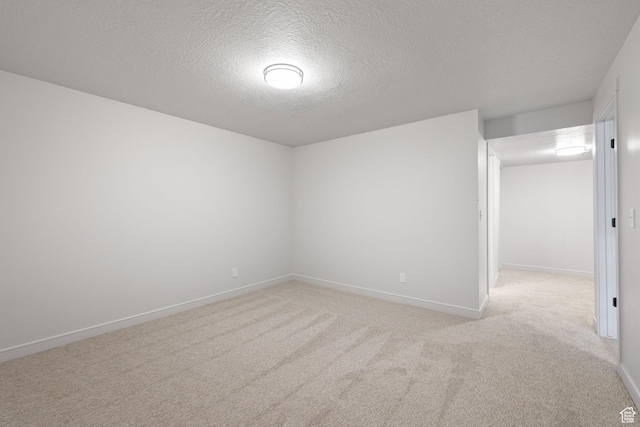 unfurnished room featuring a textured ceiling, carpet flooring, and baseboards