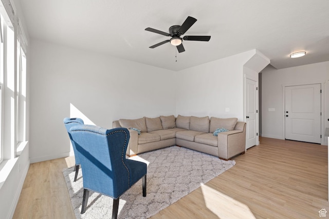 living area with light wood-style floors, ceiling fan, and baseboards