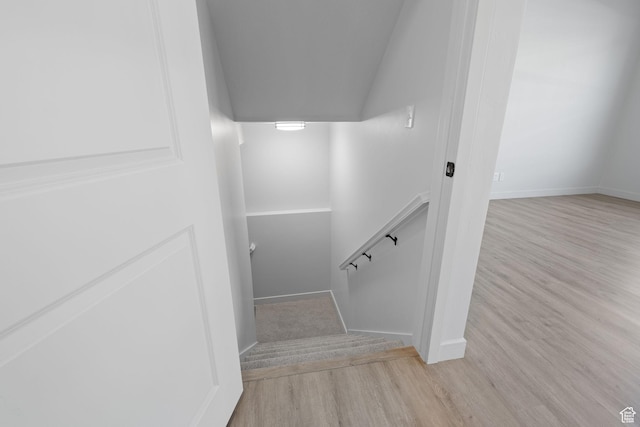 stairs with vaulted ceiling, wood finished floors, and baseboards
