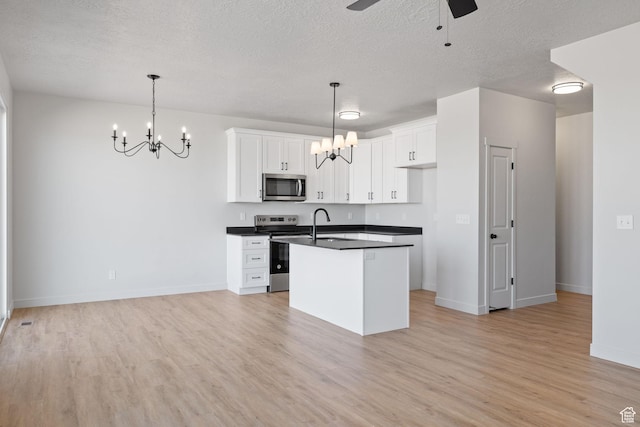 kitchen with dark countertops, light wood finished floors, appliances with stainless steel finishes, and white cabinets
