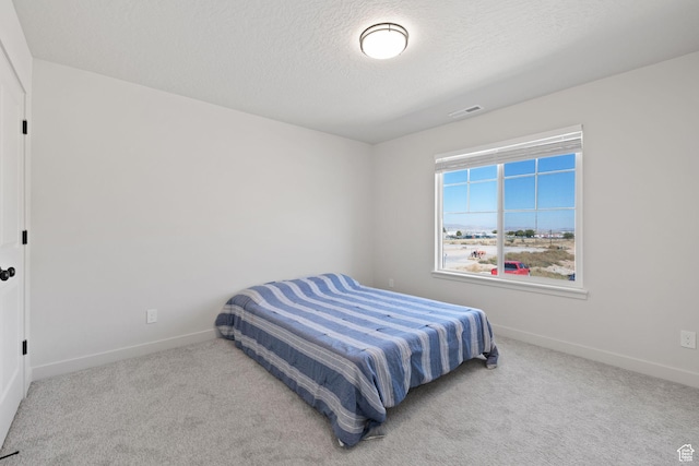 carpeted bedroom featuring visible vents, a textured ceiling, and baseboards