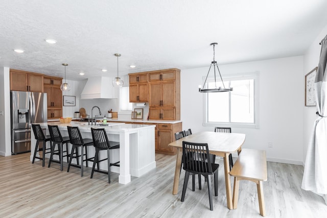 93 N 200 W, Smithfield, UT 84335 - kitchen with light countertops, hanging light fixtures, custom exhaust hood, stainless steel fridge with ice dispenser, and an island with sink