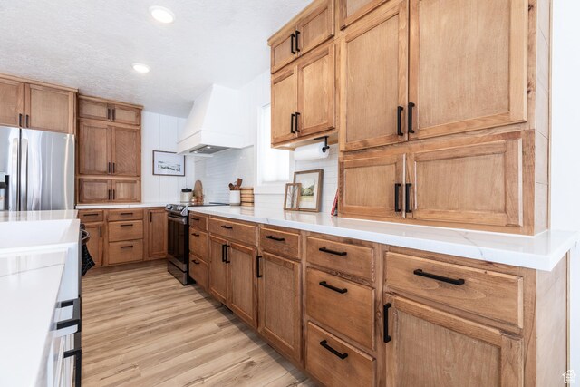 93 N 200 W, Smithfield, UT 84335 - kitchen featuring light wood finished floors, custom exhaust hood, stainless steel appliances, light countertops, and decorative backsplash