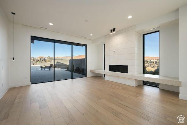 2655 W Shoshoni Trl, St George, UT 84770 - unfurnished living room featuring light wood-style flooring, a tiled fireplace, and recessed lighting