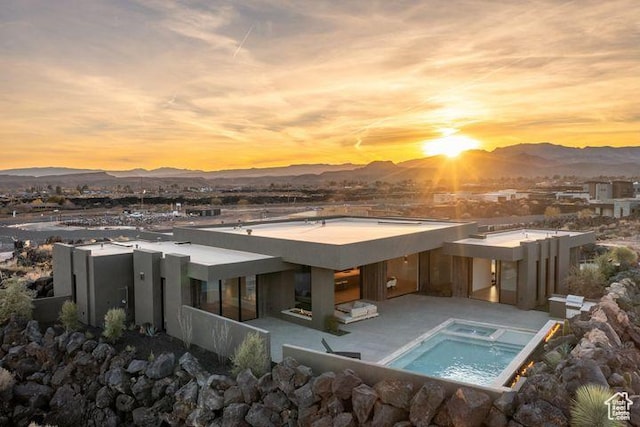2655 W Shoshoni Trl, St George, UT 84770 - back of property at dusk with an in ground hot tub, a patio area, a mountain view, and stucco siding