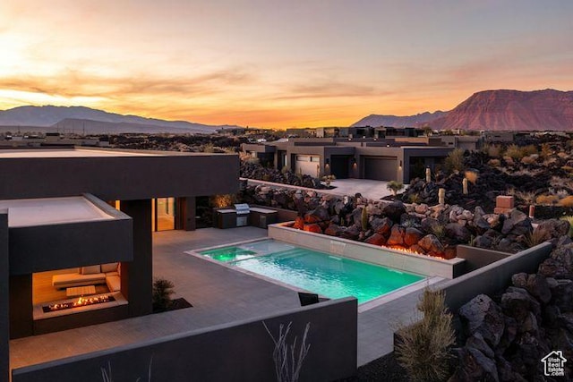 pool at dusk featuring a grill, a mountain view, an outdoor pool, and a patio
