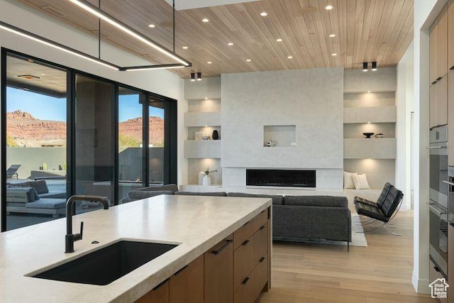2655 W Shoshoni Trl, St George, UT 84770 - kitchen featuring a fireplace, light countertops, open floor plan, a sink, and modern cabinets