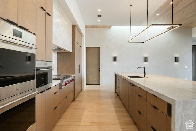 2655 W Shoshoni Trl, St George, UT 84770 - kitchen featuring decorative light fixtures, stainless steel gas stovetop, light wood-style floors, a sink, and modern cabinets