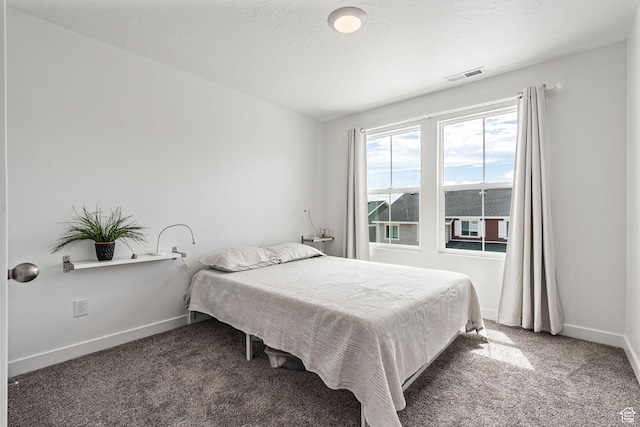 bedroom featuring visible vents, dark carpet, a textured ceiling, and baseboards