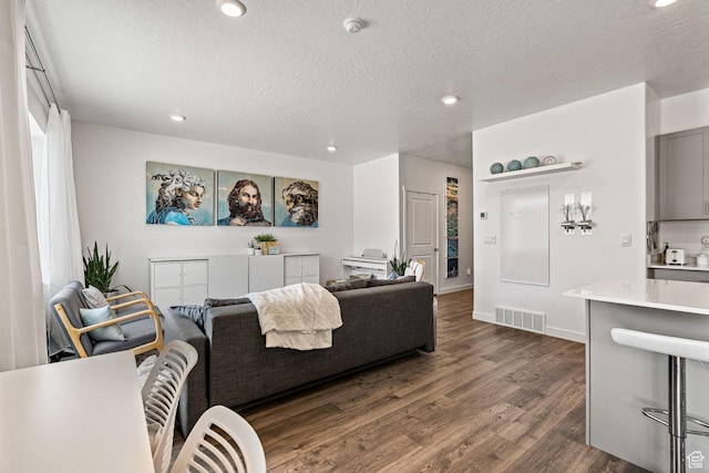 living area featuring a textured ceiling, dark wood-style flooring, visible vents, and recessed lighting