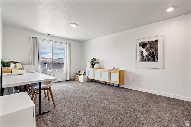 office with visible vents, dark carpet, a textured ceiling, and baseboards