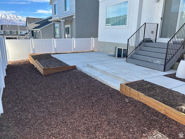 exterior space with a mountain view, a garden, a patio, and fence