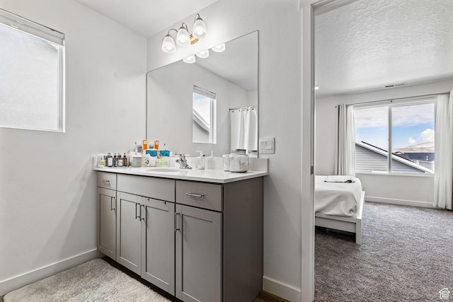 full bathroom featuring a textured ceiling, baseboards, connected bathroom, and vanity