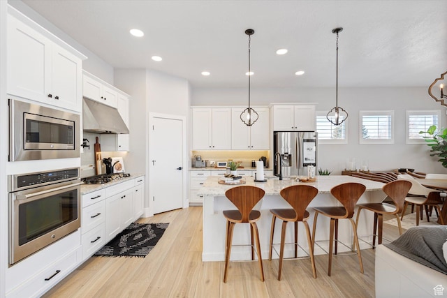 2321 E John Holladay Ct S, Holladay, UT 84117 - kitchen featuring a center island with sink, white cabinets, appliances with stainless steel finishes, hanging light fixtures, and under cabinet range hood