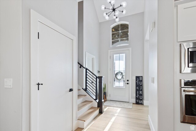 2321 E John Holladay Ct S, Holladay, UT 84117 - foyer featuring an inviting chandelier, high vaulted ceiling, light wood-type flooring, baseboards, and stairs