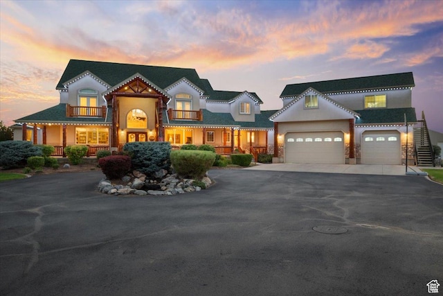 view of front of house with an attached garage, stucco siding, driveway, and a balcony