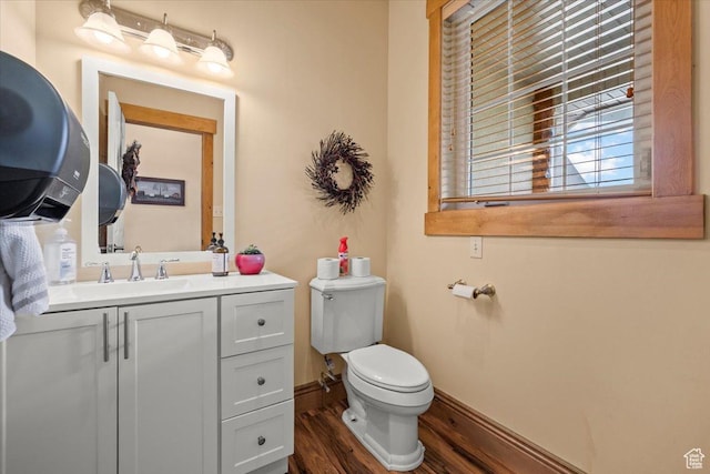 half bath with vanity, baseboards, toilet, and wood finished floors