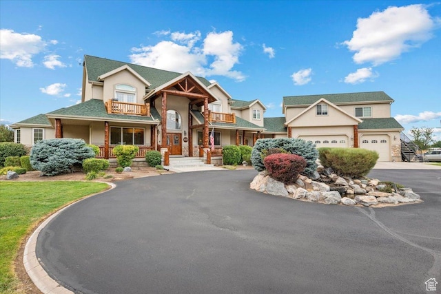 view of front of home featuring aphalt driveway, stucco siding, covered porch, and a balcony
