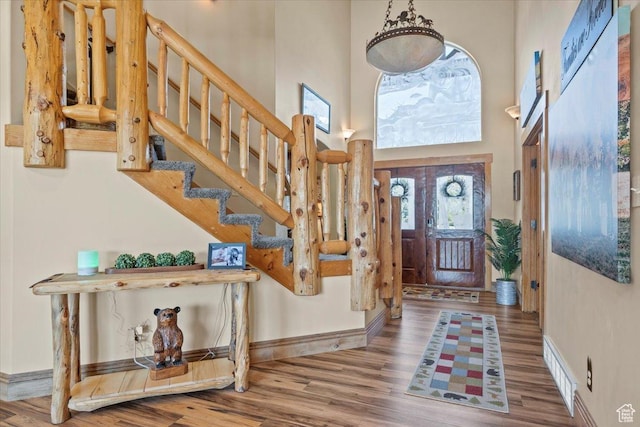 entryway with stairway, a high ceiling, baseboards, and wood finished floors
