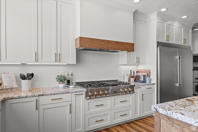 kitchen with backsplash, white cabinets, appliances with stainless steel finishes, and light wood finished floors