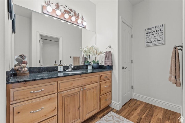 bathroom with wood finished floors, vanity, and baseboards