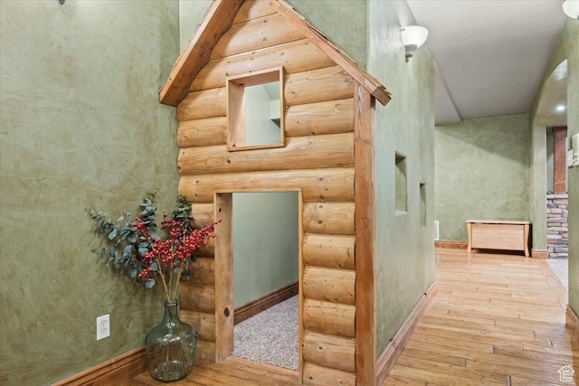 hallway featuring log walls and hardwood / wood-style floors