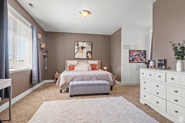 bedroom with a textured ceiling, carpet flooring, baseboards, and visible vents