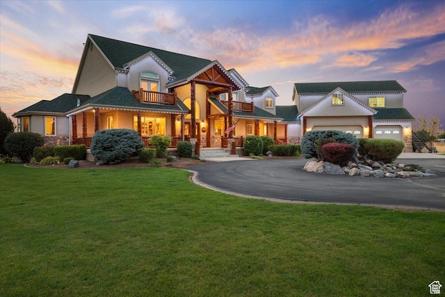 view of front facade with aphalt driveway, a front lawn, and a balcony