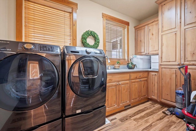 washroom featuring light wood finished floors, washing machine and dryer, and cabinet space