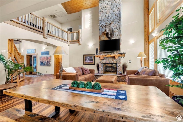 living area featuring a high ceiling, wood finished floors, a fireplace, and stairs