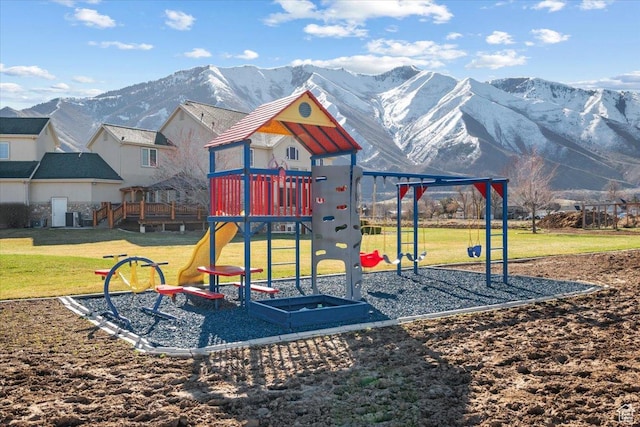 community playground with central AC, a mountain view, and a lawn