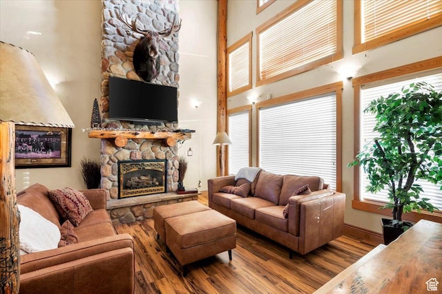 living area featuring a fireplace, a high ceiling, and wood finished floors