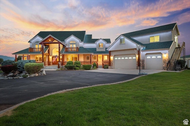 view of front of property with stucco siding, a front lawn, a balcony, an attached garage, and driveway
