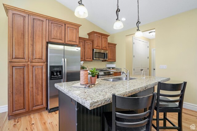 1429 E Chateau Ridge Way S, Sandy, UT 84092 - kitchen featuring a center island with sink, appliances with stainless steel finishes, brown cabinetry, a sink, and light stone countertops