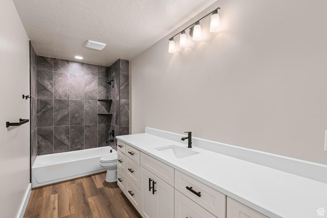 full bathroom featuring a textured ceiling, shower / bathtub combination, toilet, wood finished floors, and vanity