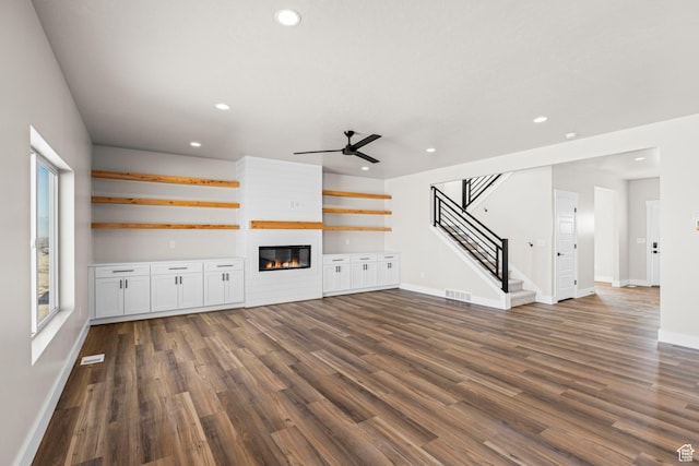 unfurnished living room featuring stairs, a fireplace, dark wood-style flooring, and recessed lighting