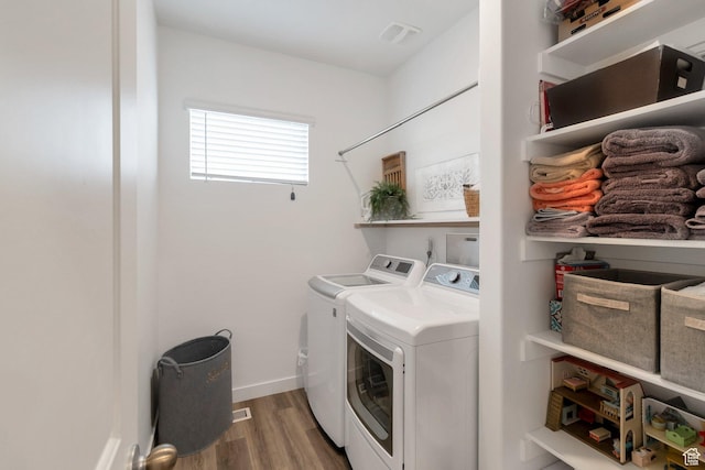 laundry area featuring laundry area, baseboards, visible vents, washer and clothes dryer, and wood finished floors