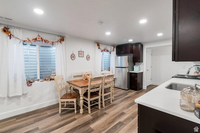 kitchen with wood finished floors, a sink, light countertops, dark brown cabinets, and freestanding refrigerator