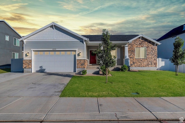 craftsman house with an attached garage, stone siding, a front lawn, and concrete driveway