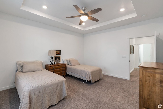 carpeted bedroom with baseboards and a raised ceiling