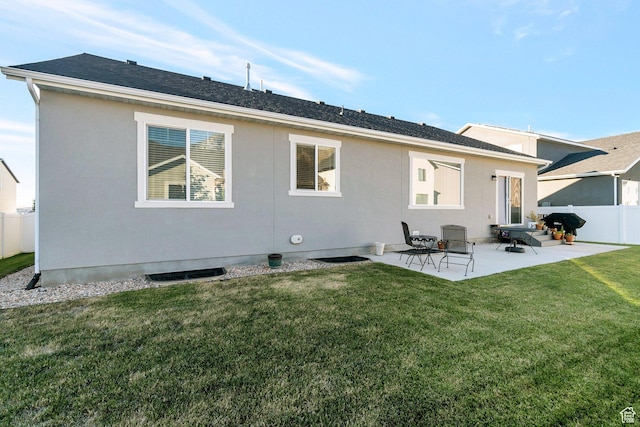 rear view of house featuring roof with shingles, a yard, a patio, stucco siding, and fence