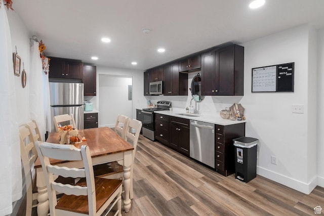 kitchen featuring stainless steel appliances, light wood finished floors, light countertops, and dark brown cabinetry