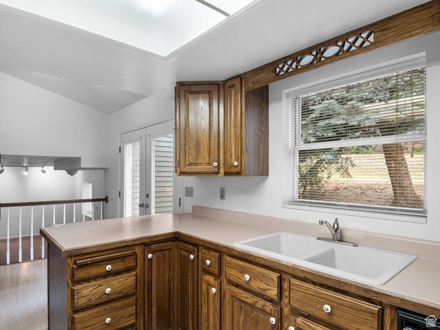 kitchen featuring a peninsula, a sink, wood finished floors, light countertops, and french doors