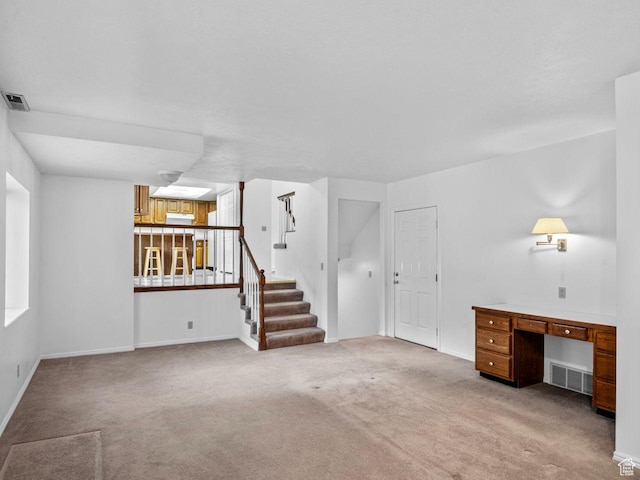 unfurnished living room featuring visible vents, light carpet, stairway, and baseboards