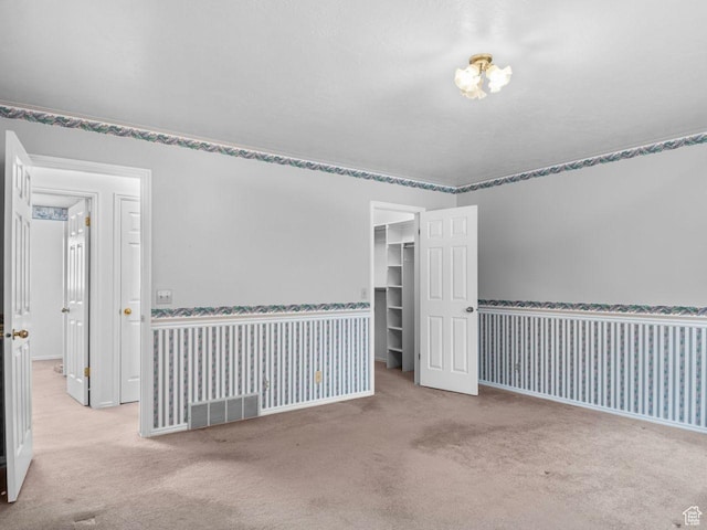 empty room with light carpet, wallpapered walls, baseboards, and visible vents