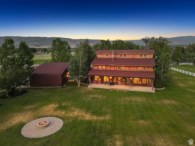 703 River Rd, Midway, UT 84049 - back of property at dusk with a patio area, a mountain view, an outdoor structure, a metal roof, and a fire pit
