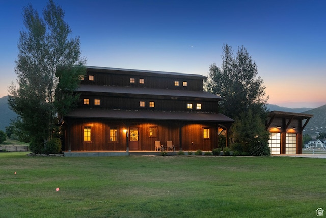 703 River Rd, Midway, UT 84049 - back of house at dusk featuring a lawn, covered porch, and board and batten siding