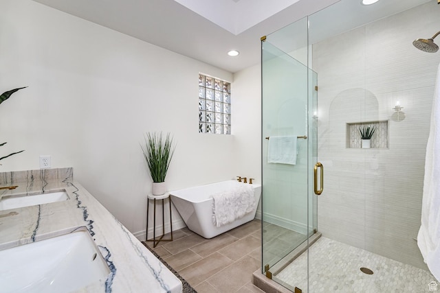 full bathroom featuring a freestanding bath, double vanity, a shower stall, and baseboards